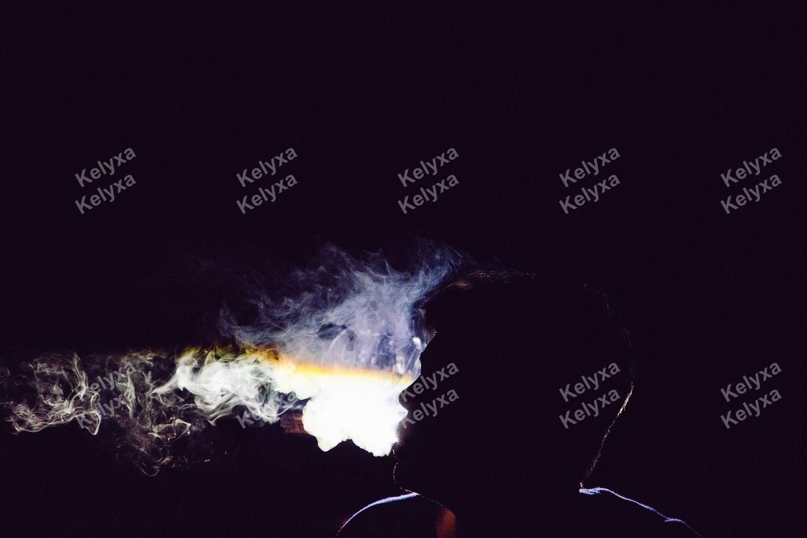 Silhouette Exhaling Smoke In Dark