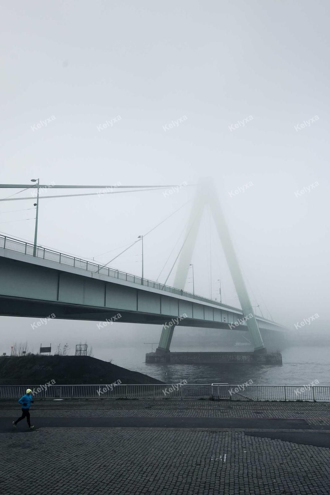 Runner Beneath Foggy Suspension Bridge